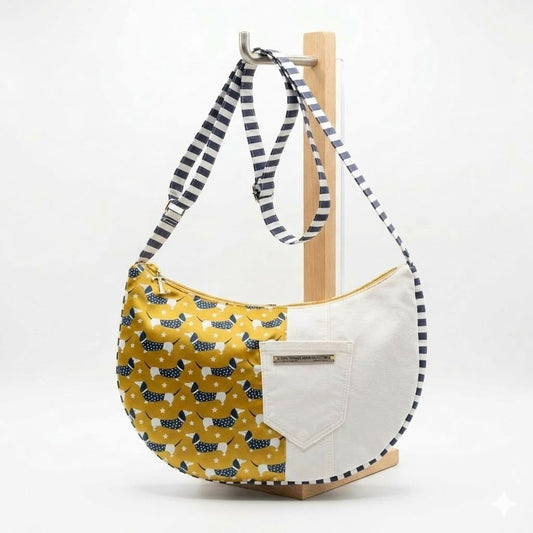 Bolso Sling Dachshund Encantos — vista frontal con bolsillo exterior en lona blanca, estampado de perritos salchicha en mostaza y bolsillo de rayas navy con borla dorada