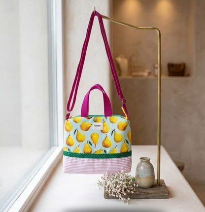 Bolso tote peras colgado en perchero dorado junto a ventana