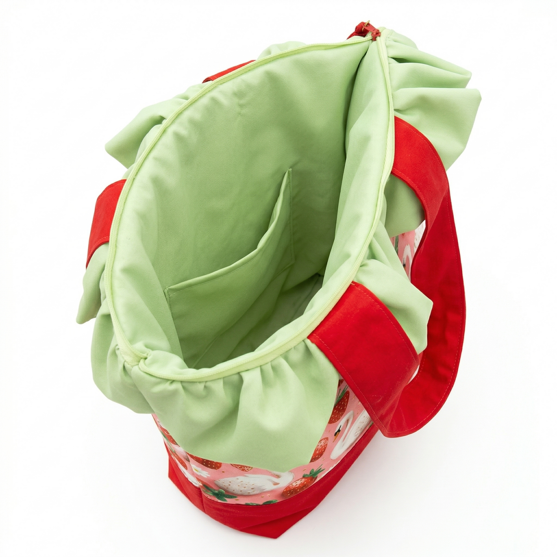 Bolso Tote Fresas con Volante Verde abierto, mostrando interior espacioso con bolsillo y asas rojas con volante verde claro alrededor.