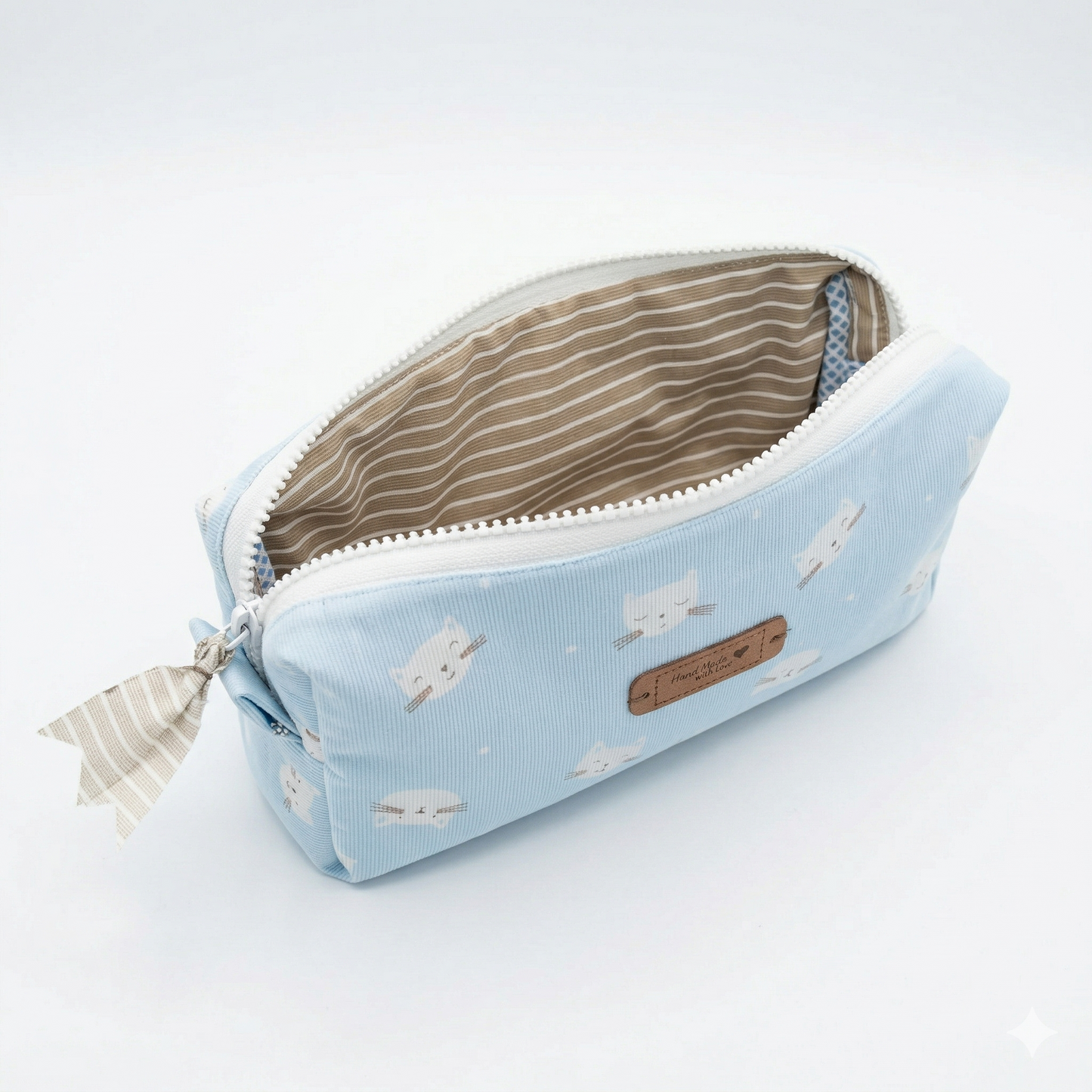 Neceser Gatitos Azul Cielo con diseño de gatitos blancos, tejido azul claro y cierre con cremallera, interior forrado a rayas beige.