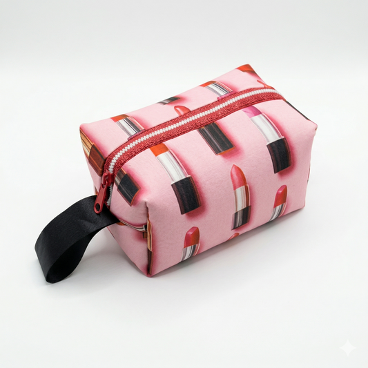 Neceser Labiales Love | Encantos con diseño de labiales rojos sobre fondo rosa, cierre rojo y asa negra para facilitar su transporte.