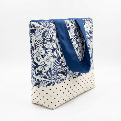 Bolso Tote Playa Azul Tropical con Volante, con estampado floral azul y blanco combinado con base beige de lunares negros y asas azules resistentes.