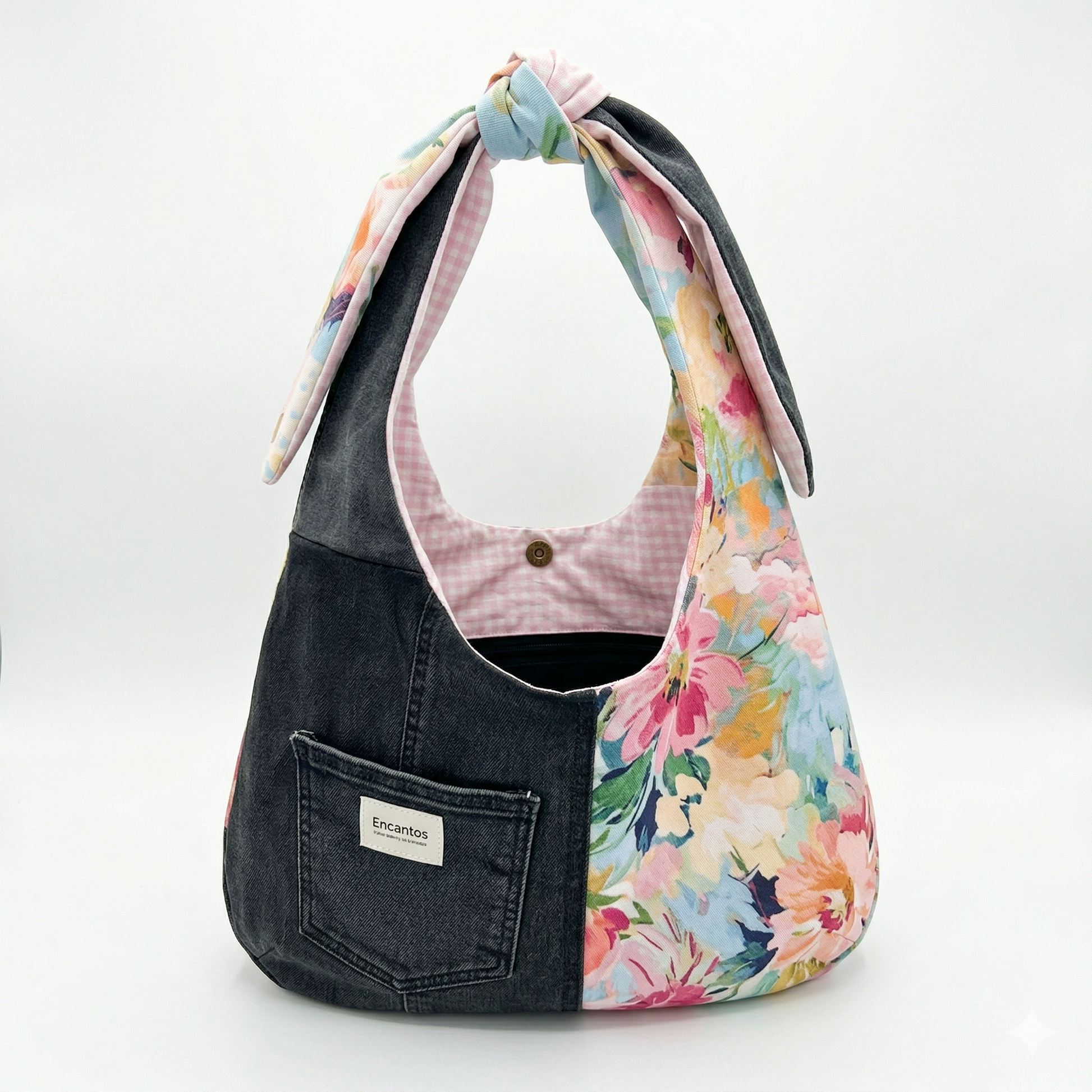 Bolsa Hobo Denim & Flores | Encantos combinando mezclilla oscura y tela con estampado floral en tonos pastel, con cierre abotonado y diseño moderno con nudo en la asa.