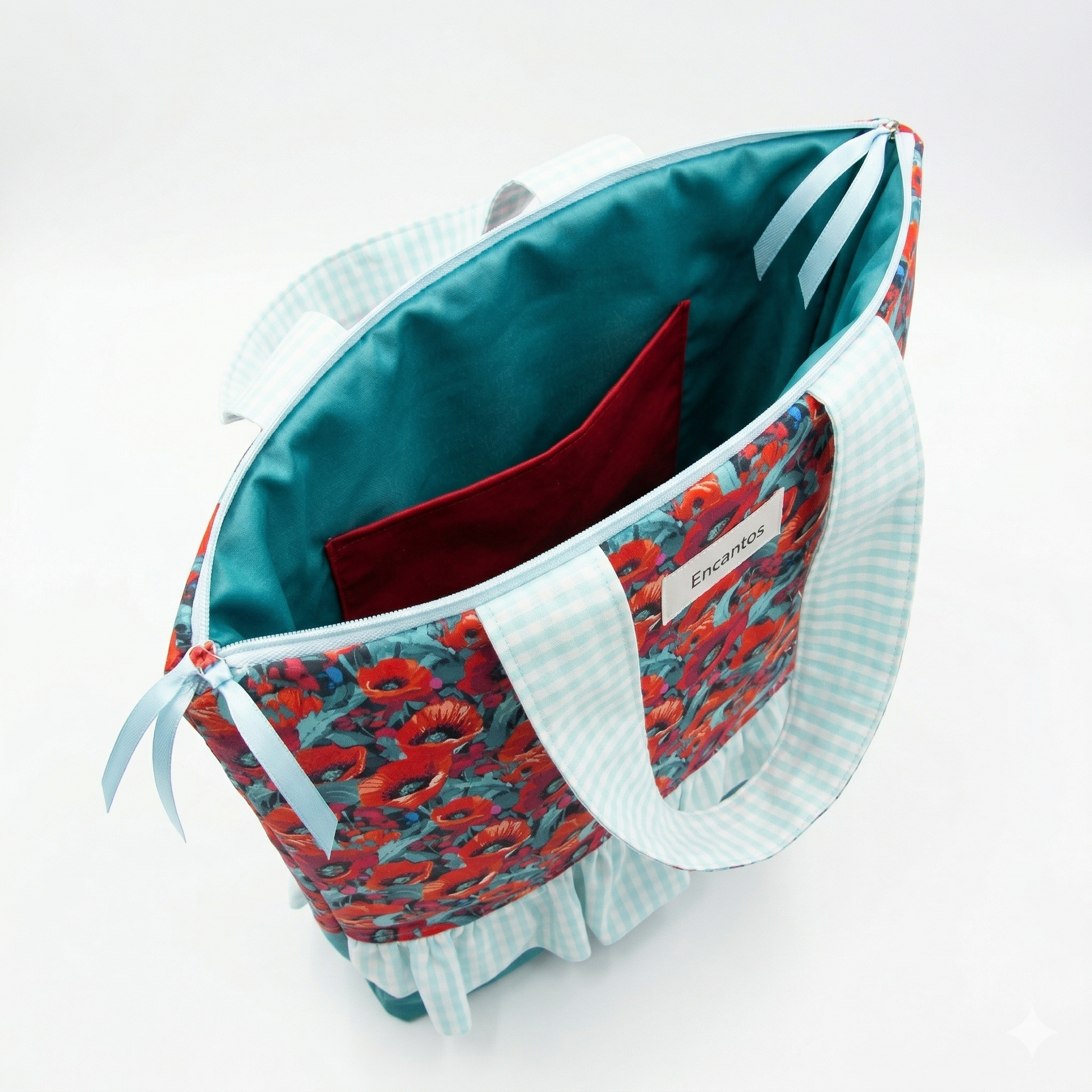Bolso Cuquito con Amapolas y Volante abierto mostrando interior forrado azul con bolsillo rojo, asas a cuadros celestes y diseño exterior de amapolas rojas.