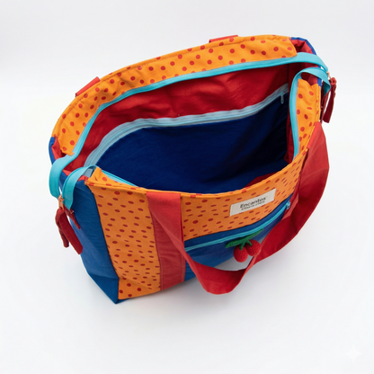 Bolsa Tote Cerezas — Encantos vista desde arriba mostrando interior espacioso azul y detalles naranjas con puntos rojos y asas en rojo y azul.