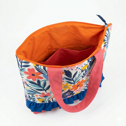 Bolso Tote Floral con Volante con diseño colorido de flores, asas rosas y volante azul, interior naranja con compartimentos para mejor organización.