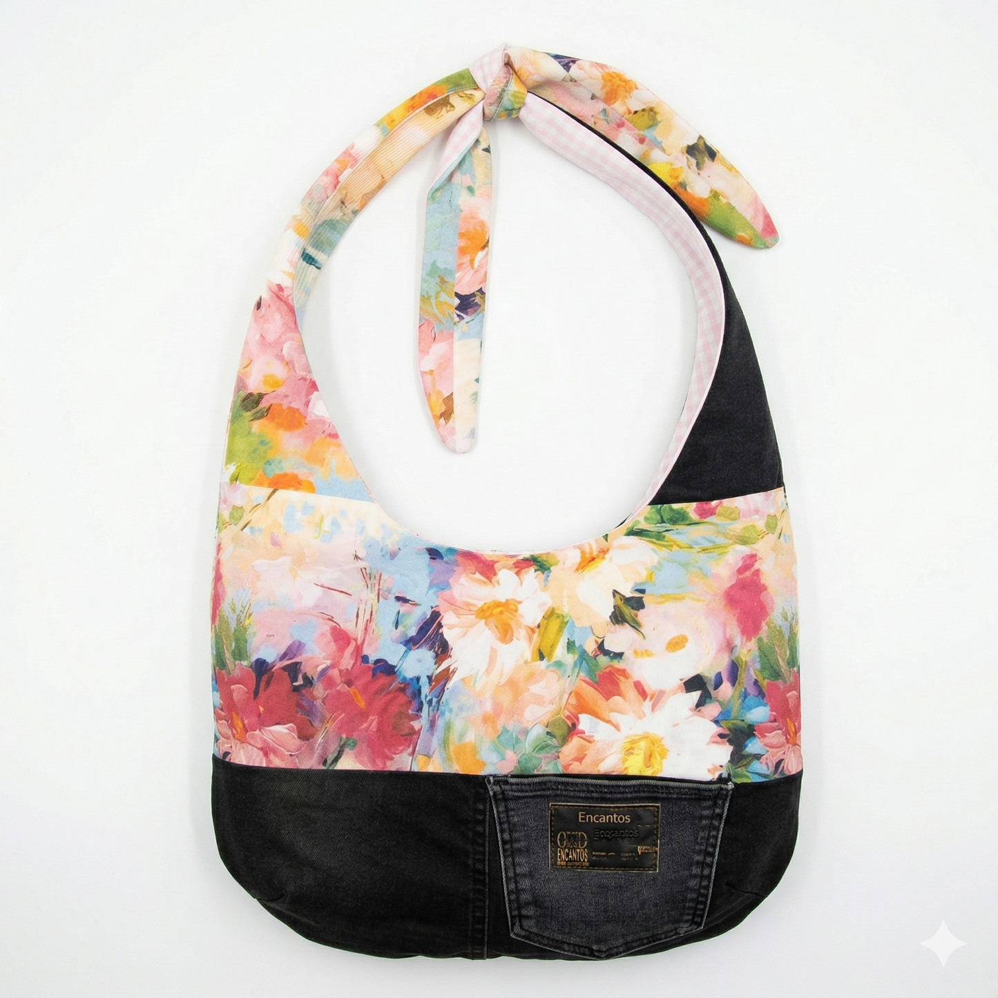 Bolsa Hobo Denim & Flores | Encantos, mochila de tela con diseño floral colorido y base de mezclilla negra con detalle de bolsillo frontal.