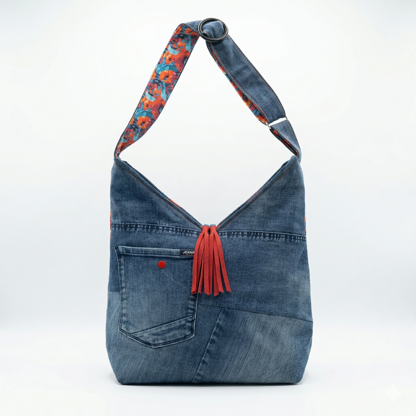 Bolso Hobo Amapolas | Encantos en tela mezclilla con detalle de borla roja y asa con diseño de amapolas en colores vivos.
