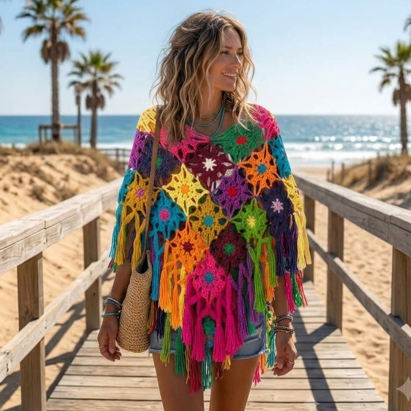 Modelo con poncho crochet multicolor en pasarela de madera frente a la playa